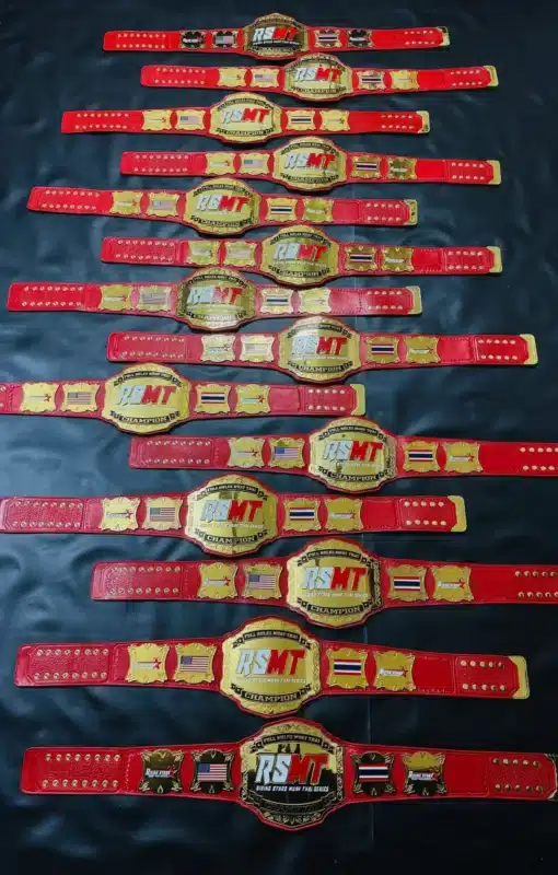 Front view of the Rising Stars Muay Thai Championship Belts featuring a red leather strap and gold-plated plates.