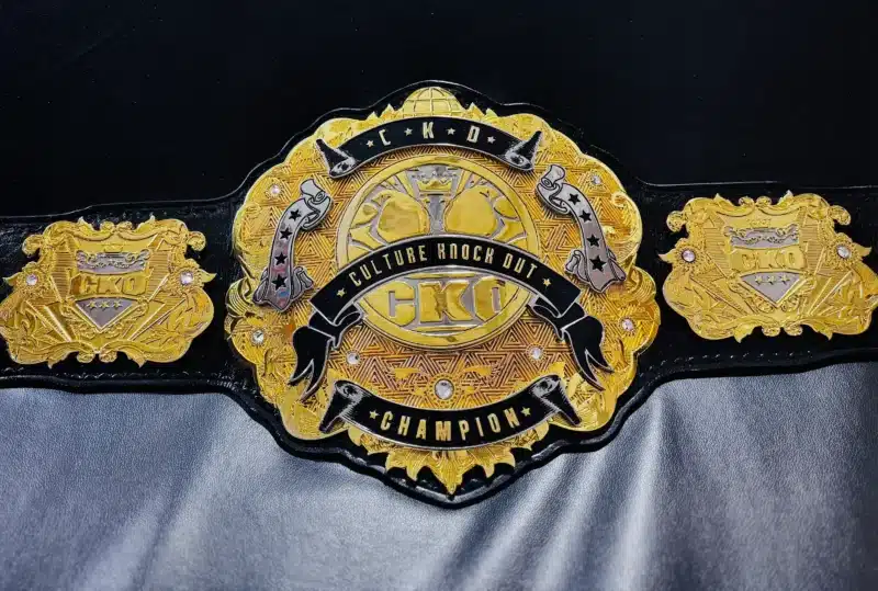 Close-up of a custom corporate championship belt with engraved logo on a multi-layered gold plate.