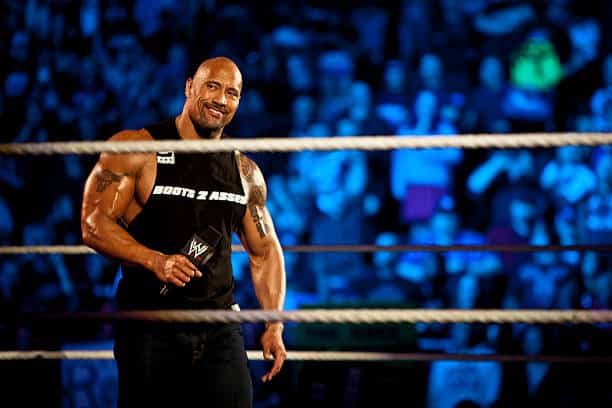 The Rock holds the WWF Championship belt in the ring, showing his iconic confidence.