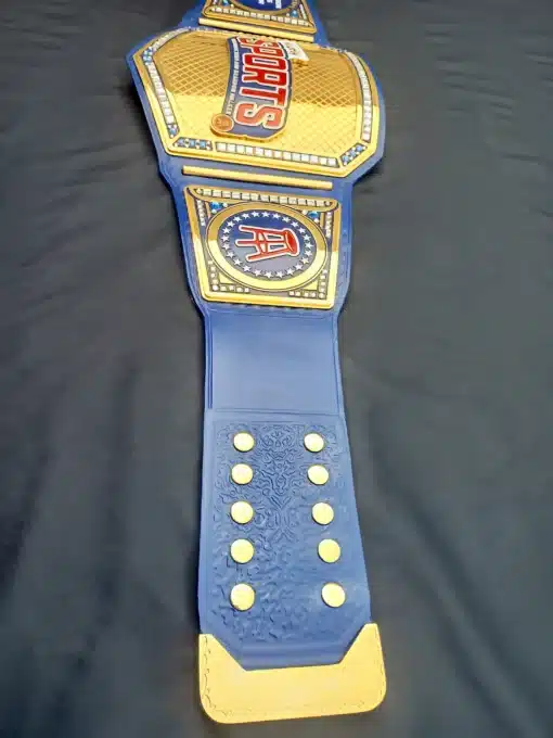 Championship belt featuring a blue leather strap with gold accents and crystals.