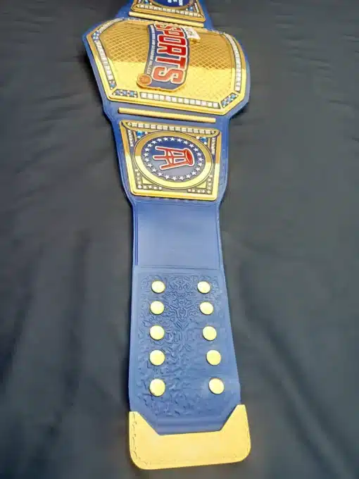 Championship belt featuring a blue leather strap with gold accents and crystals.