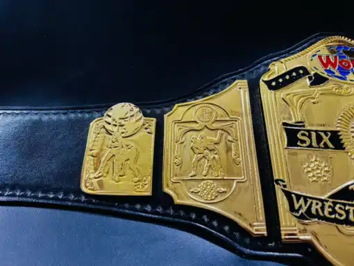 Close-up of gold-plated side plates with intricate wrestling-themed engravings, TV-accurate replica.