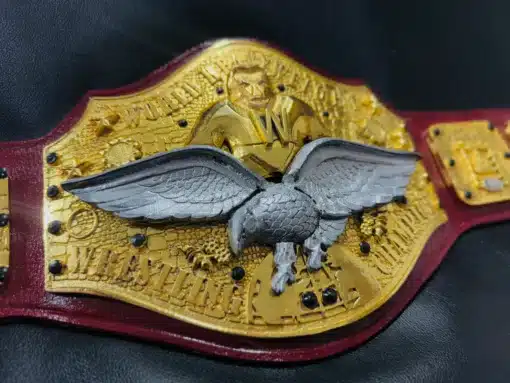 Stunning silver eagle centerpiece on a gold championship belt with vintage wrestling artwork.