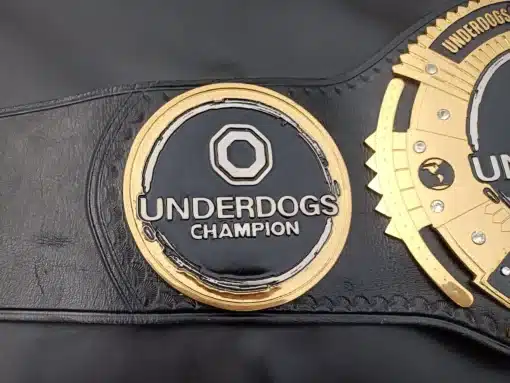 Side view of the Underdogs Champion Belt showing intricate gold-plated side plates with sharp etching details.