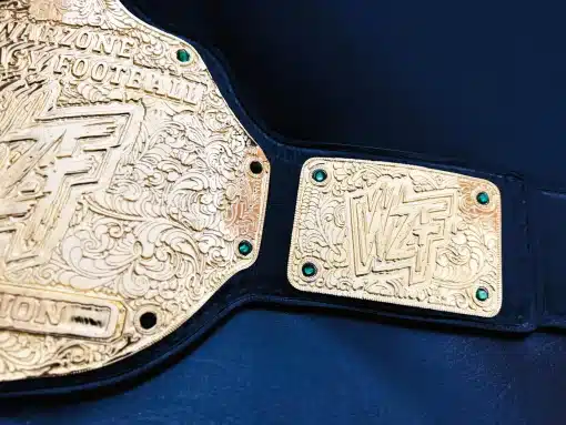 Detailed side view of Warzone Fantasy Football championship belt showing 4mm thick zinc plates, intricate nugget texture engraving, and premium leather strap.